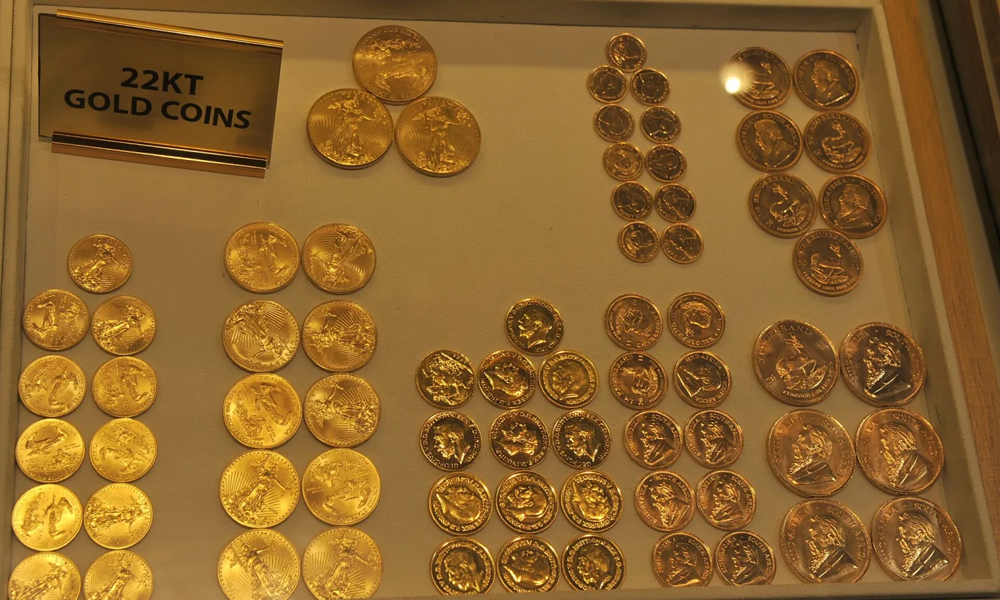 A dealer's display case labelled 22KT GOLD COINS, holding American Gold Eagles at the left alongside South African Krugerrands and British sovereigns