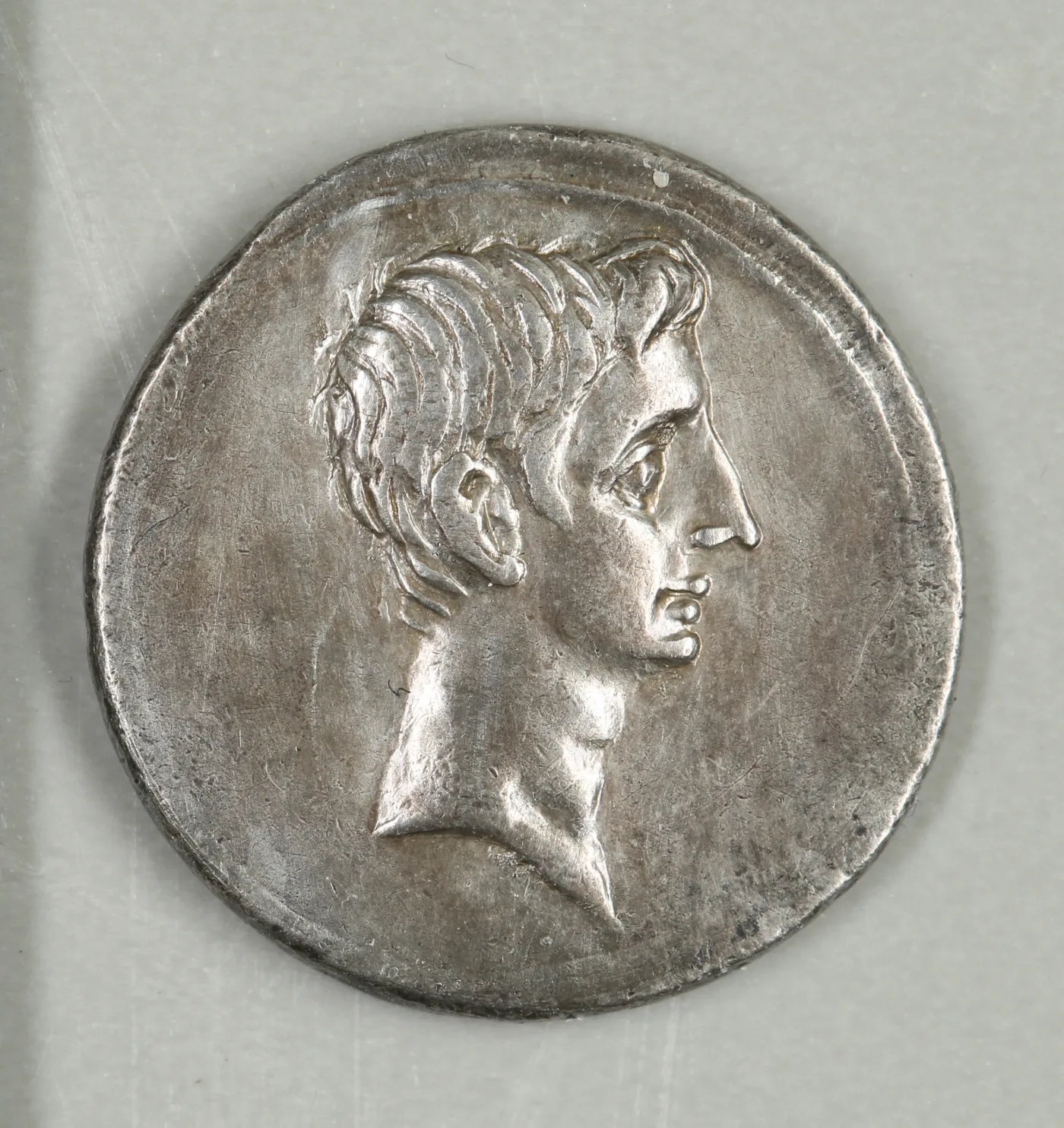 Obverse of a silver denarius of Octavian, bare head facing right, with no inscription anywhere in the field