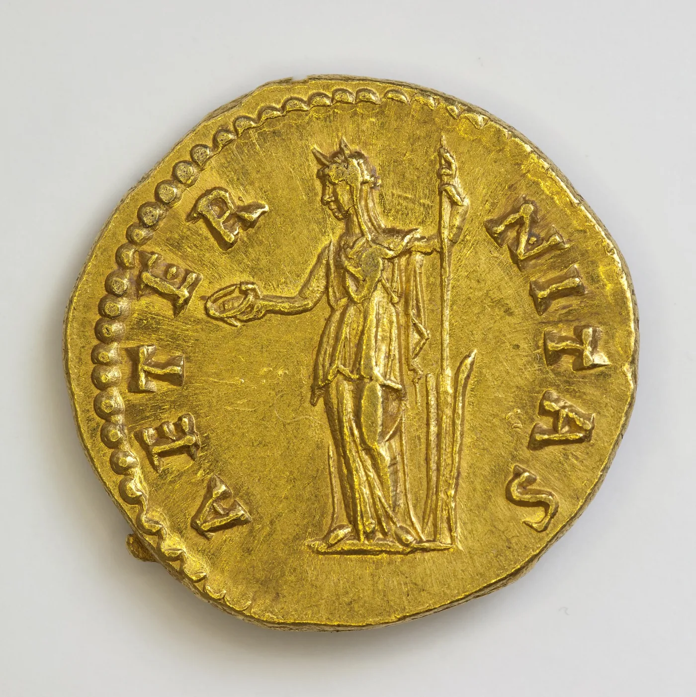 Reverse of the same gold aureus, a draped figure standing left holding a small bird on a globe in the extended right hand and a long sceptre in the left, legend AETERNITAS around
