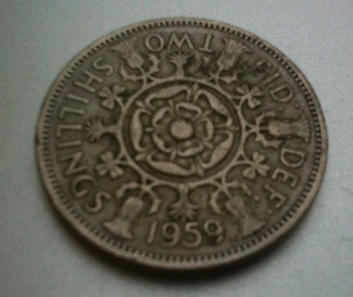 Reverse of a 1959 British florin, a Tudor rose at the centre surrounded by thistles and shamrocks, with FID DEF and the date