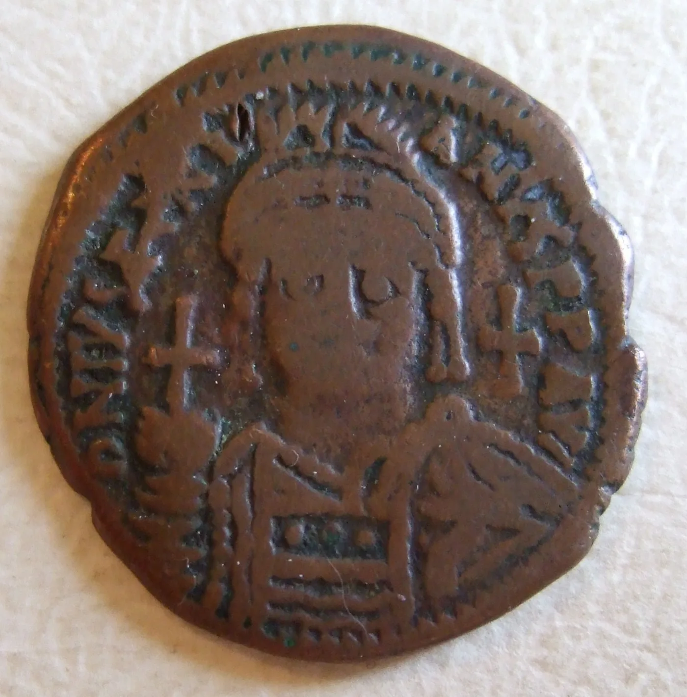 Copper Byzantine follis showing a crowned facing bust with a cross on the crown, filling almost the entire coin