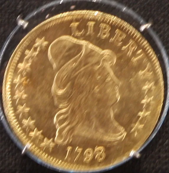 Obverse of a Capped Bust eagle photographed through a plastic holder, slightly blurred, with the date 1798 legible below the bust