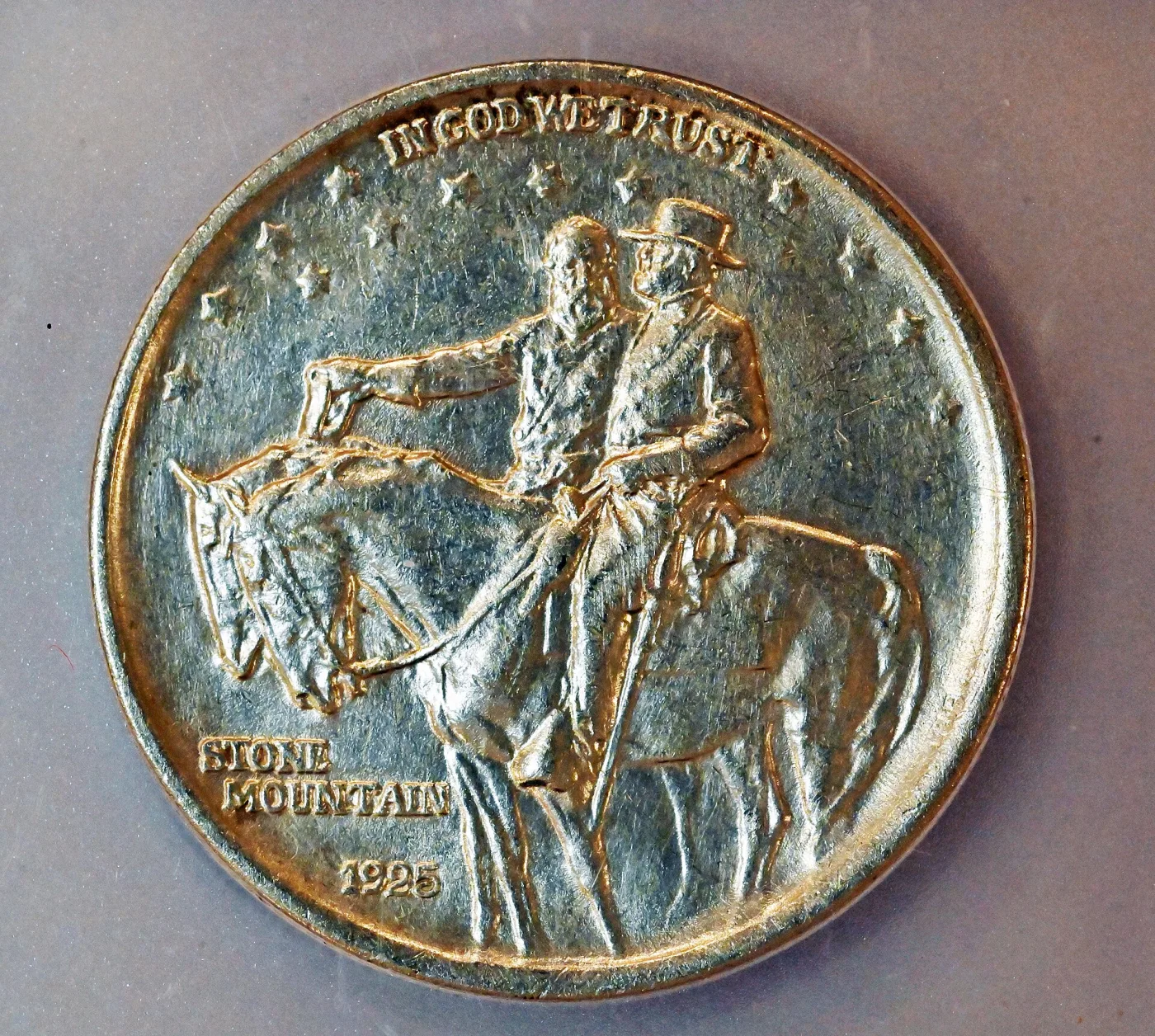 Obverse of a Stone Mountain Memorial half dollar showing two mounted figures riding to the left beneath IN GOD WE TRUST, with STONE MOUNTAIN and 1925 at the lower left