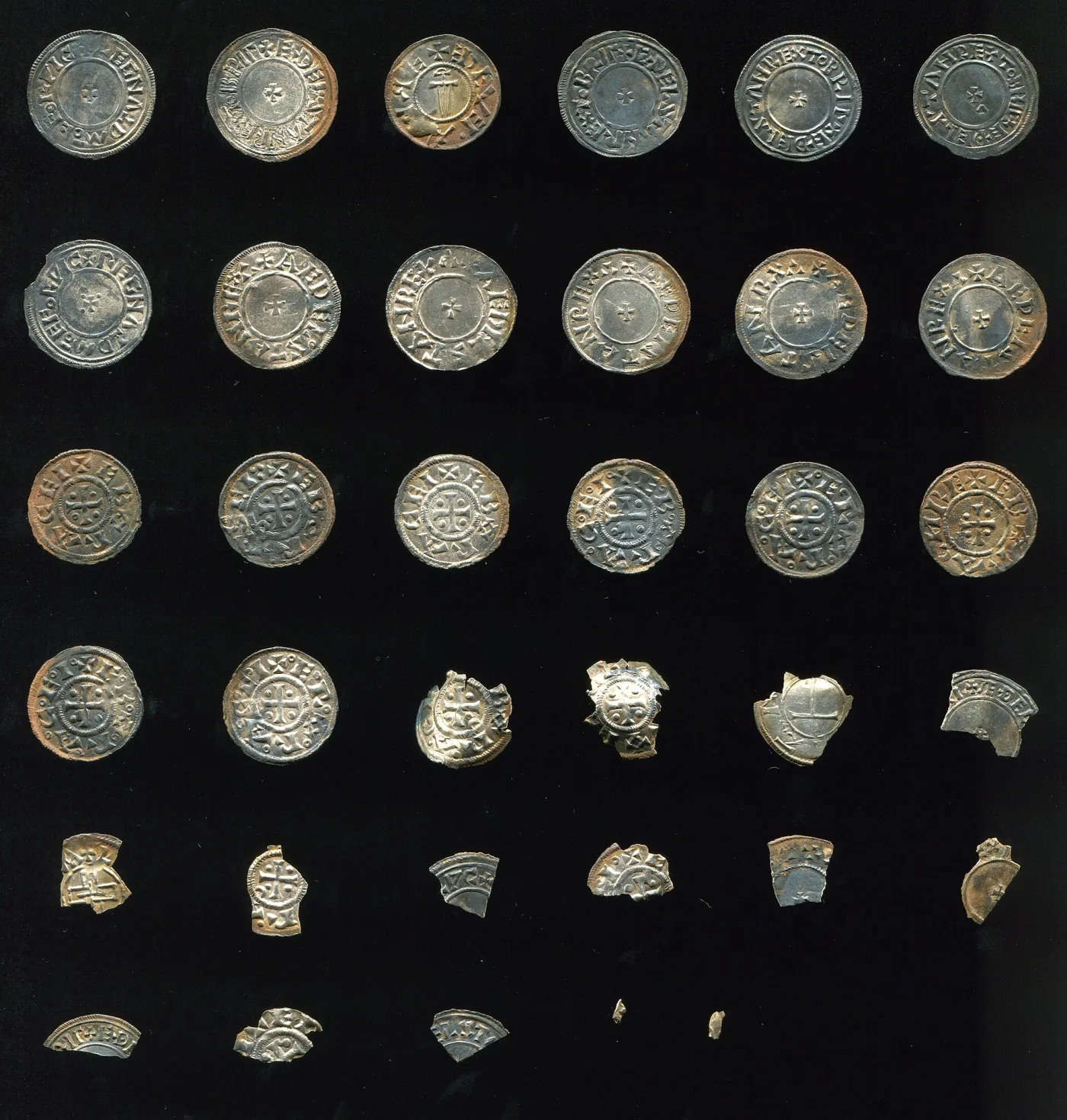 A second group of small medieval silver coins from the same hoard, arranged on a dark background