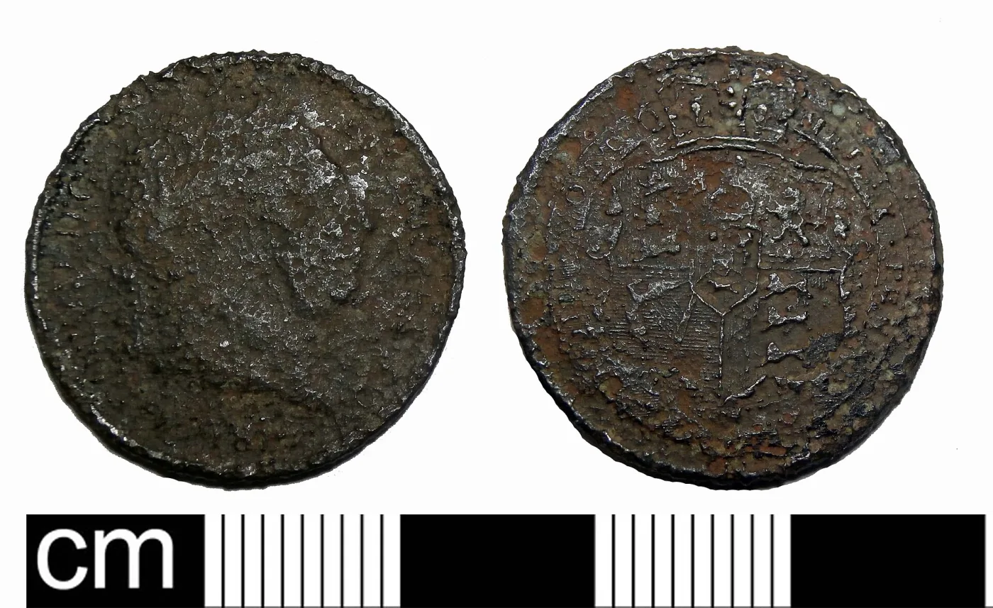 Two faces of a worn silver-coloured shilling of George III photographed beside a scale