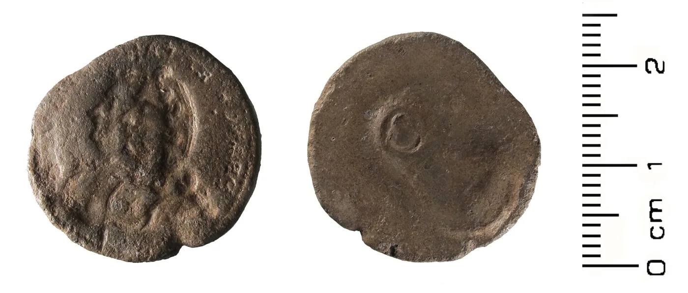 Two faces of a small lead-alloy disc, one bearing a sunken impression of a coin design and the other nearly blank