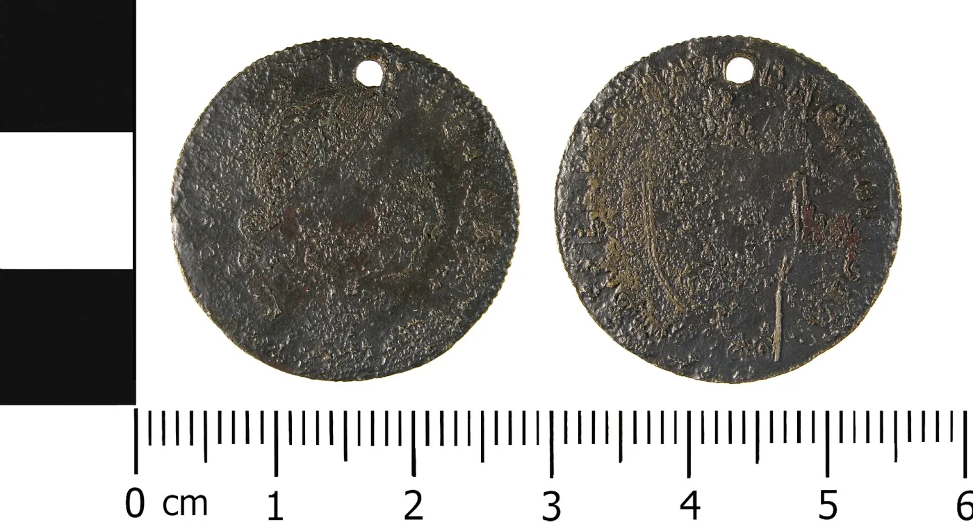 Two faces of a brass-coloured disc imitating a George III guinea, with a portrait on one side and a shield on the other