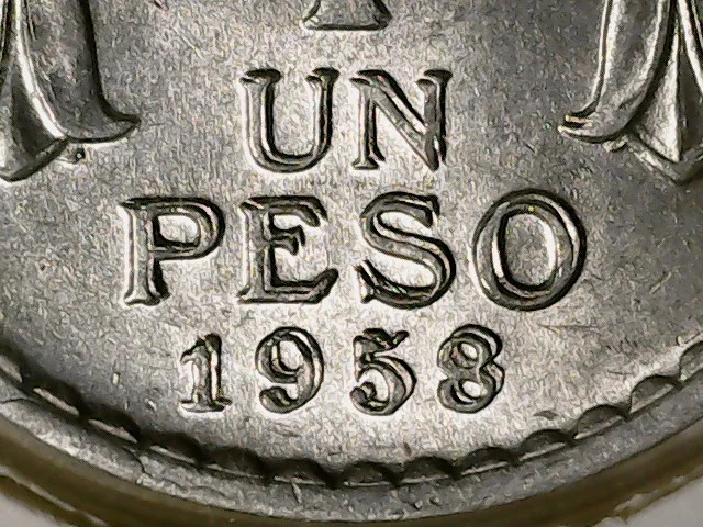 Close-up of the words UN PESO and the date 1958 on a Chilean coin, the letters and numerals showing clear doubling
