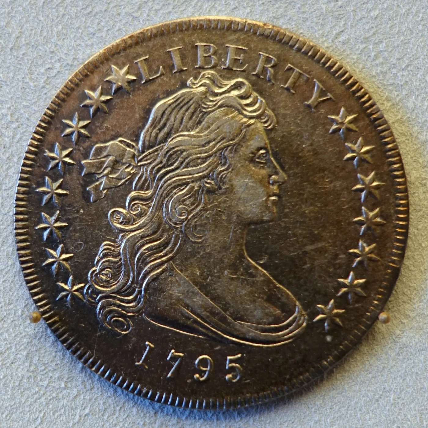 Obverse of a deeply toned 1795 Draped Bust dollar showing fifteen stars, eight in the left field and seven in the right, with the date 1795 below the bust