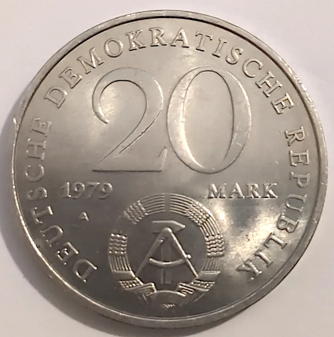 A 1979 East German 20 Mark, the legend DEUTSCHE DEMOKRATISCHE REPUBLIK around a large 20 with the date 1979, a letter A, MARK, and a hammer-and-compass emblem in a wheat wreath below