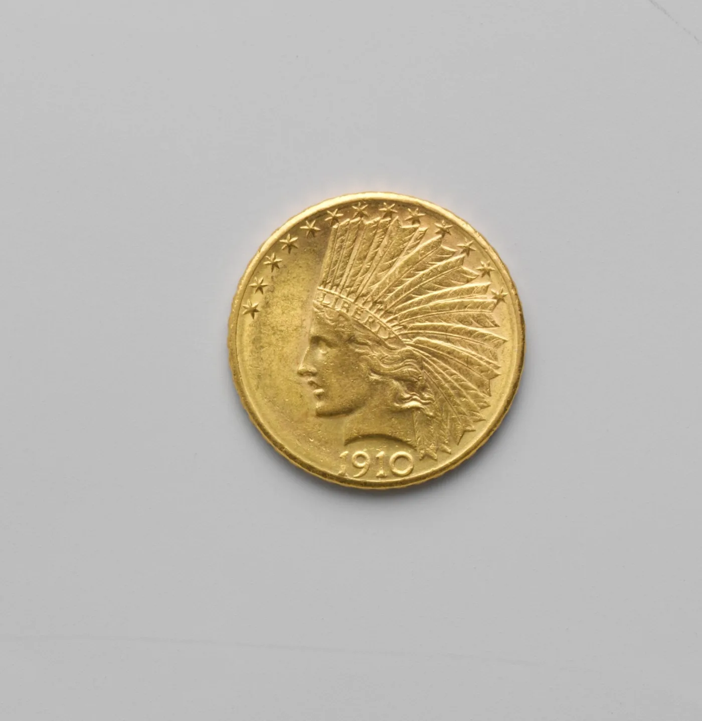 Obverse of a 1910 Indian Head eagle with an unworn cheekbone, complete LIBERTY on the headdress band and sharp feather tips