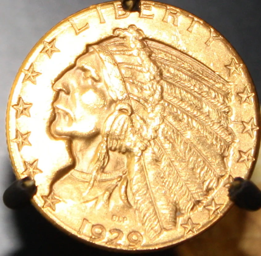 Obverse of an Indian Head half eagle dated 1929 held in a pronged coin holder, the chief in a feathered war bonnet with LIBERTY above and the date below