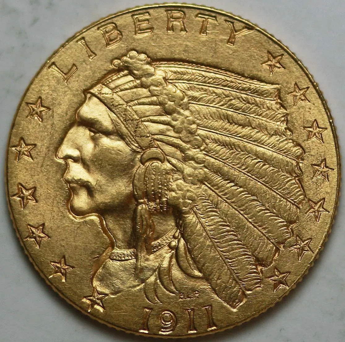 Obverse of a 1911 Indian Head quarter eagle, incuse portrait and feathered headdress, LIBERTY above, thirteen stars around the field and the date 1911 below