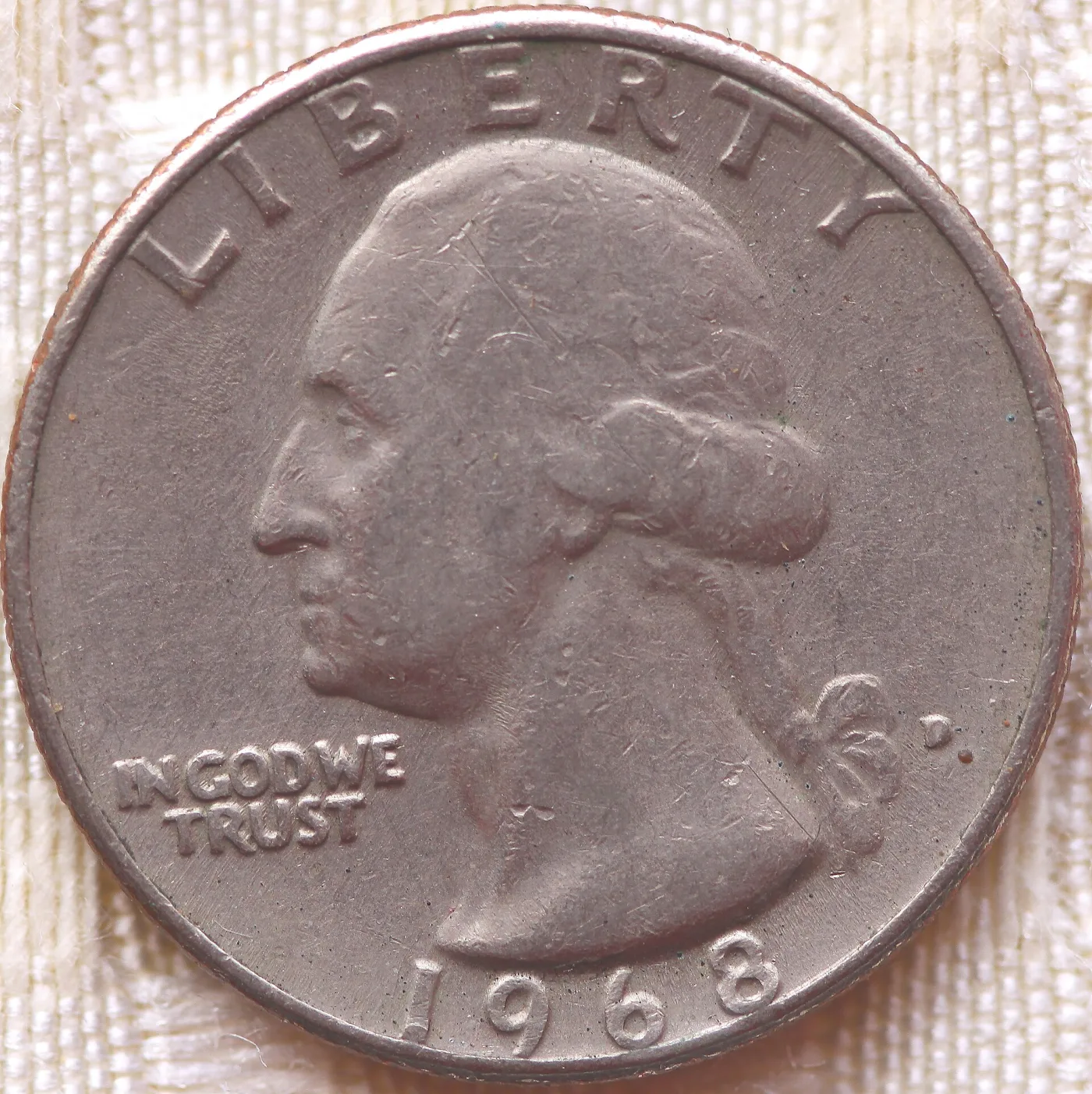 Obverse of a worn 1968-D Washington quarter in copper-nickel clad, with reddish copper showing along the rim