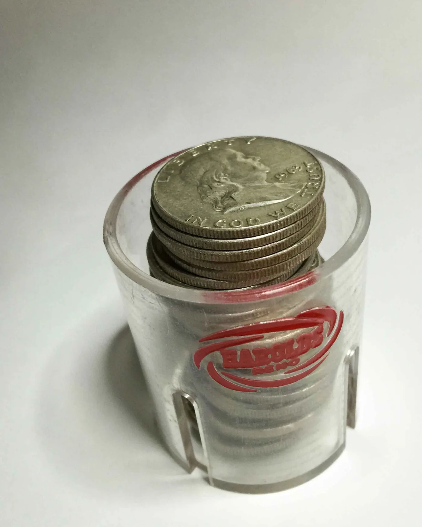 A rigid plastic coin tube holding a stack of Franklin half dollars, top coin dated 1963, with the reeded edges of the stack visible