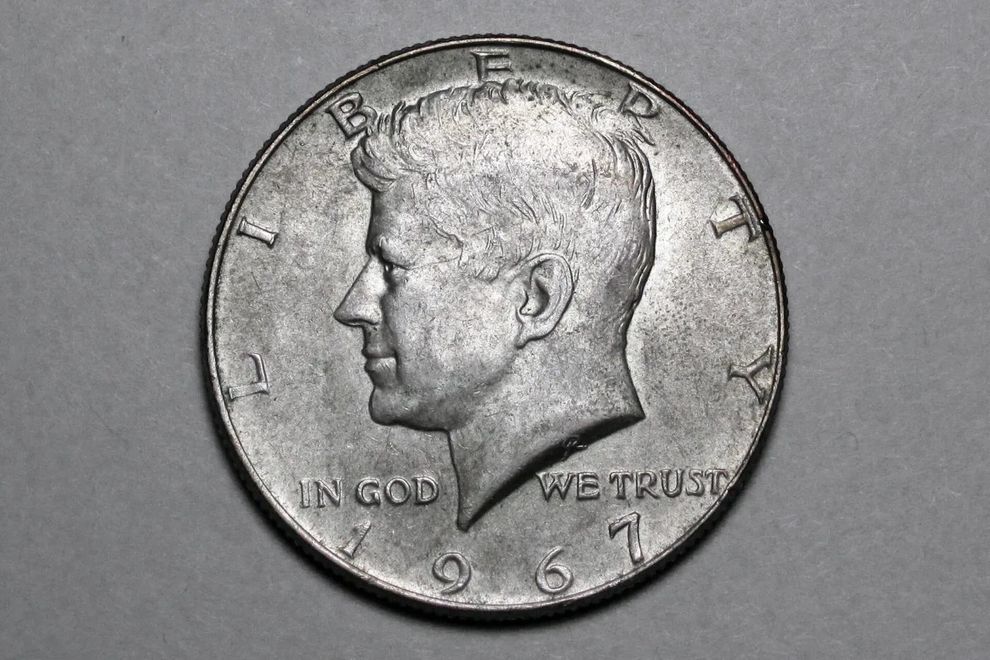 Obverse of a 1967 Kennedy half dollar, the left-facing Kennedy bust with LIBERTY broken by the top of the head, IN GOD WE TRUST in two lines and the date below