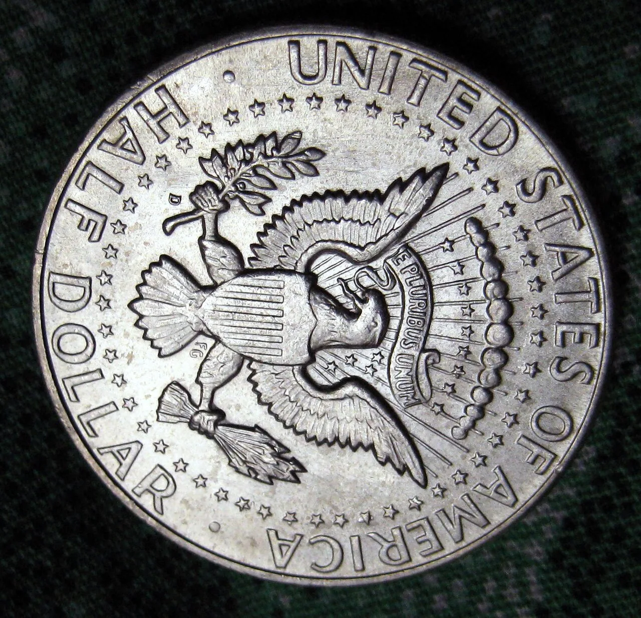 Reverse of a 1964-D Kennedy half dollar photographed upside down, with the D mint mark beside the olive branch stem