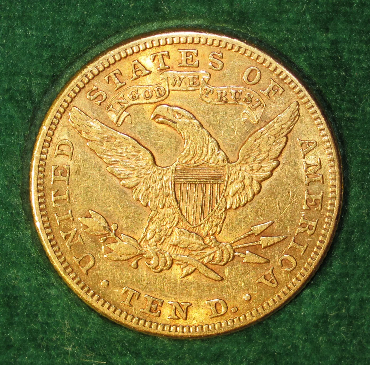 Reverse of an 1883 Philadelphia Liberty Head Eagle with the IN GOD WE TRUST scroll above the eagle and an empty field between the tail feathers and TEN D.