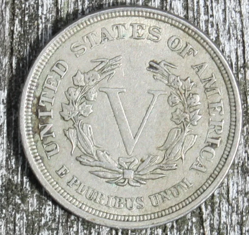 Circulated No CENTS reverse of an 1883 Liberty Head V nickel photographed on weathered wood, the wreath softened by wear but the bottom rim still clearly free of the word CENTS