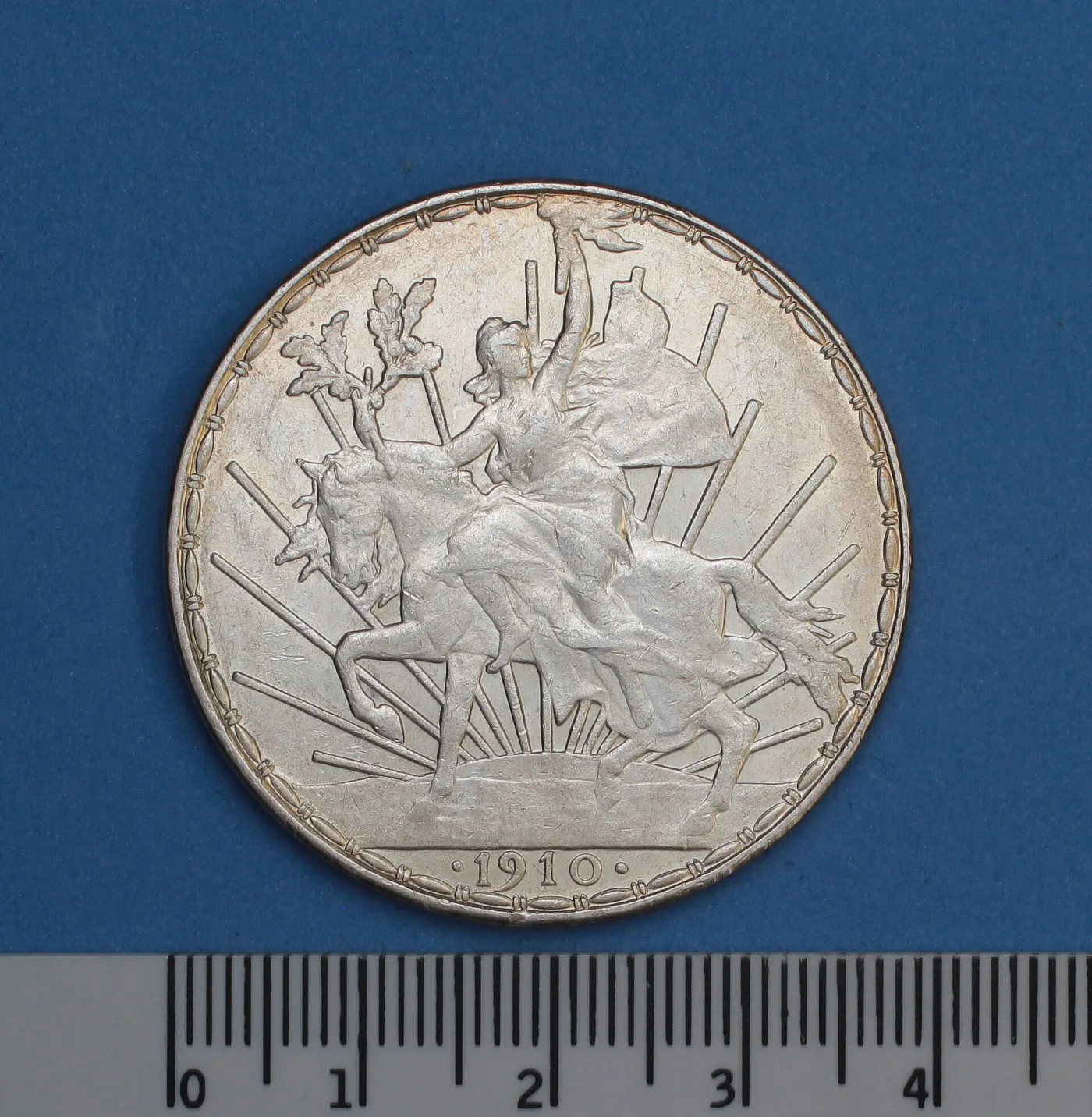 Reverse of a Mexican silver peso of 1910 showing a woman on horseback holding a torch, with the value and date below