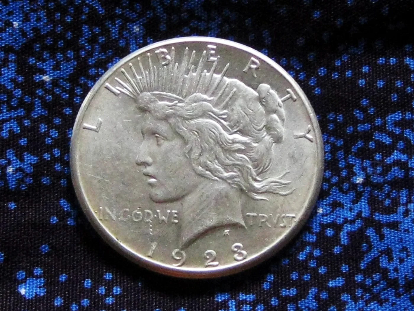Obverse of a 1923 Peace dollar lit from one side, the hair above the ear and the cheekbone catching the light as the highest points of the design