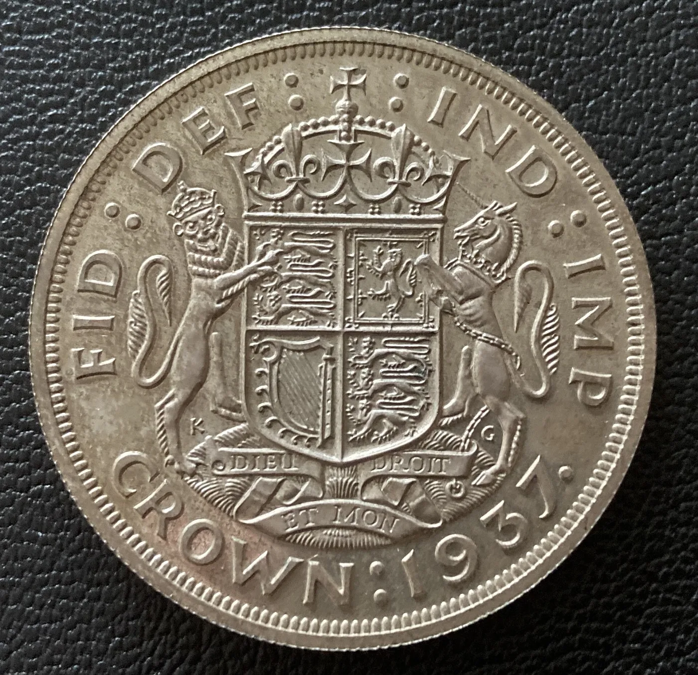 Reverse of a 1937 George VI proof crown showing the crowned quartered shield with lion and unicorn supporters, the raised design and the surrounding field reading as a single tone with no frost-to-mirror contrast