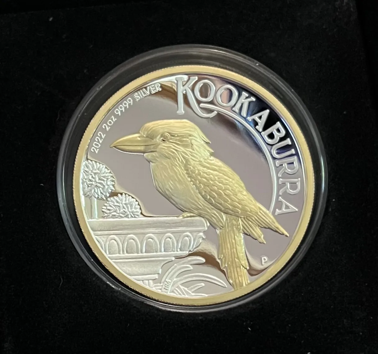 A two-ounce 2022 Kookaburra proof coin from the Perth Mint sealed in a clear round capsule and seated in a black presentation case, the bird picked out in gold against a mirrored silver field