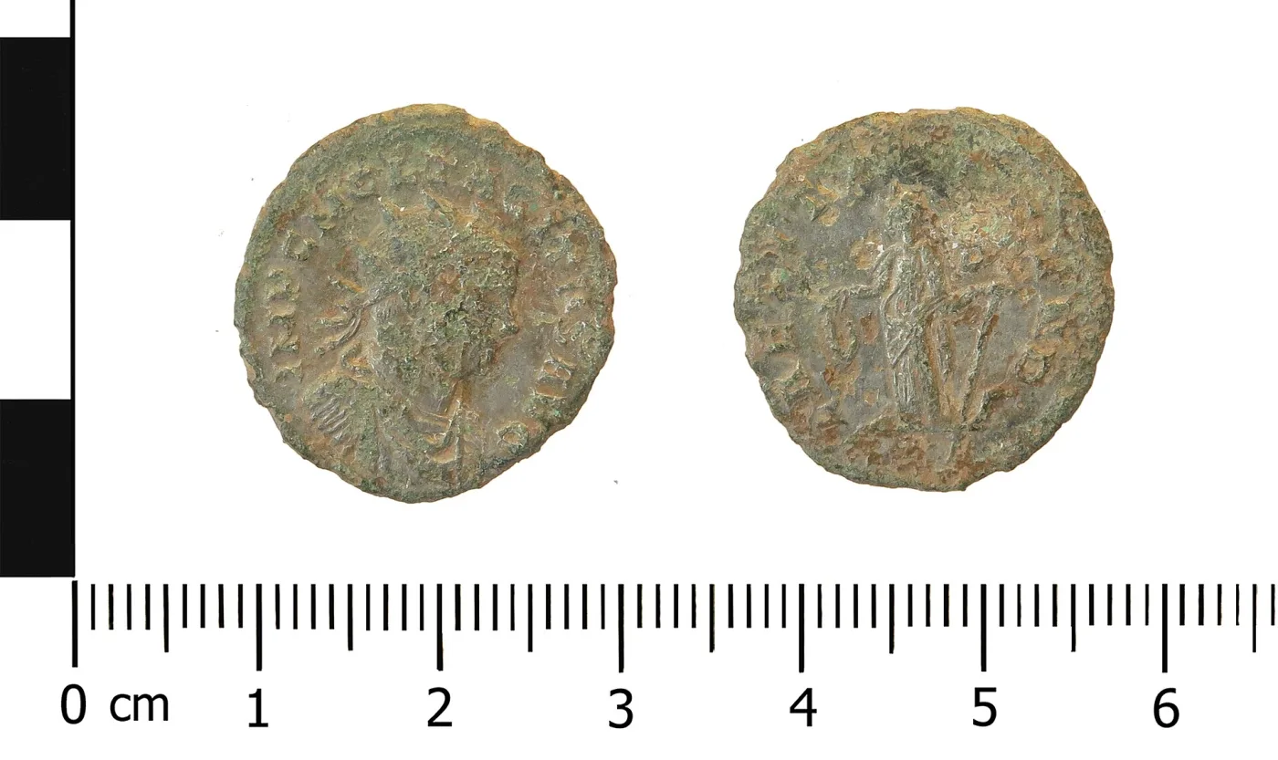 Obverse and reverse of a small Roman copper-alloy radiate of Tacitus beside a centimetre scale: a radiate draped bust, and a standing female figure holding an anchor