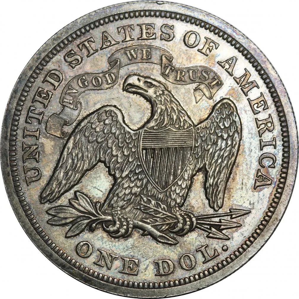 Reverse of an 1871 proof Seated Liberty dollar with the motto IN GOD WE TRUST on a banner above the eagle's head and no mint mark below the eagle