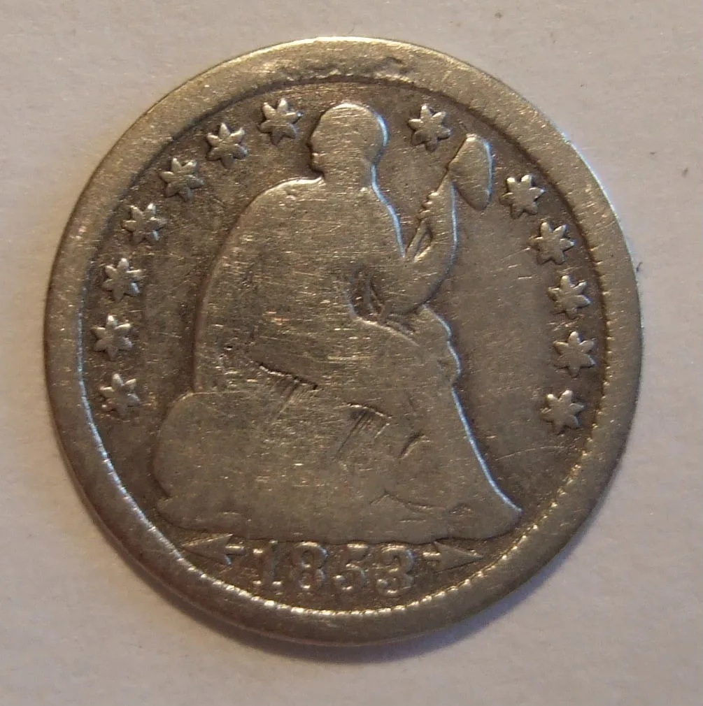 Heavily worn obverse of an 1853 Seated Liberty half dime with arrows at the date, the shield smooth and LIBERTY entirely worn away