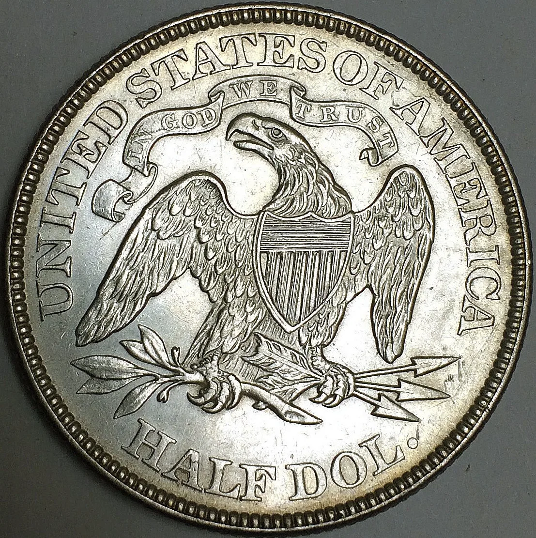 Reverse of an 1873 Seated Liberty half dollar with IN GOD WE TRUST on a ribbon-ended scroll above the eagle and no mint mark below the claws