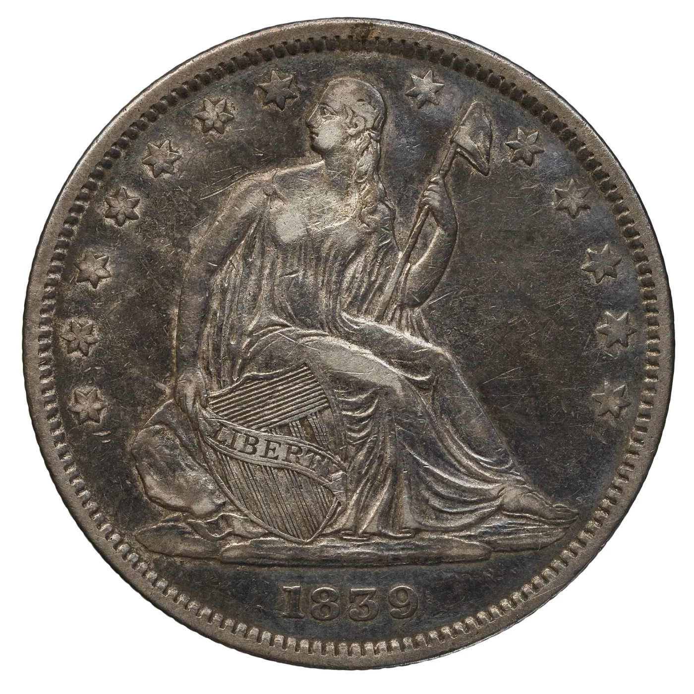 Obverse of an 1839 Seated Liberty half dollar with a fold of drapery hanging from the elbow of the arm that rests on the shield, thirteen stars and the date 1839