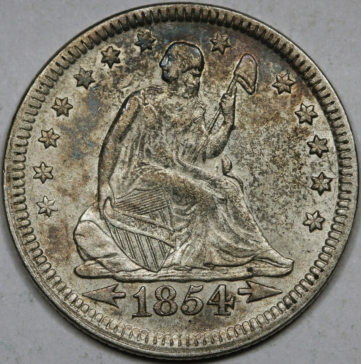 Obverse of an 1854 Seated Liberty quarter with an arrow on each side of the date, both arrowheads pointing outward toward the rim, drapery at the elbow and thirteen stars around the field