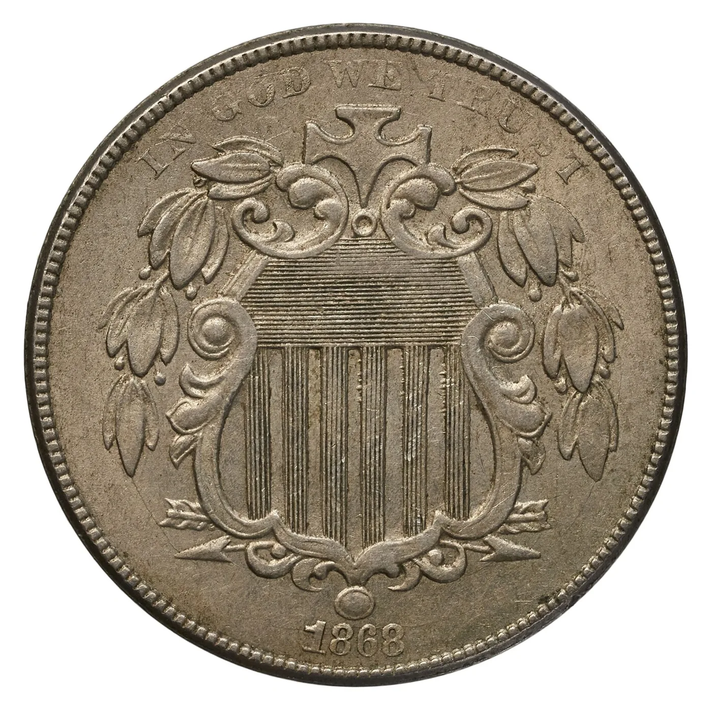 Obverse of an 1868 Shield nickel on which the letters of TRUST at the upper right are soft and partly formed while the shield below is sharp