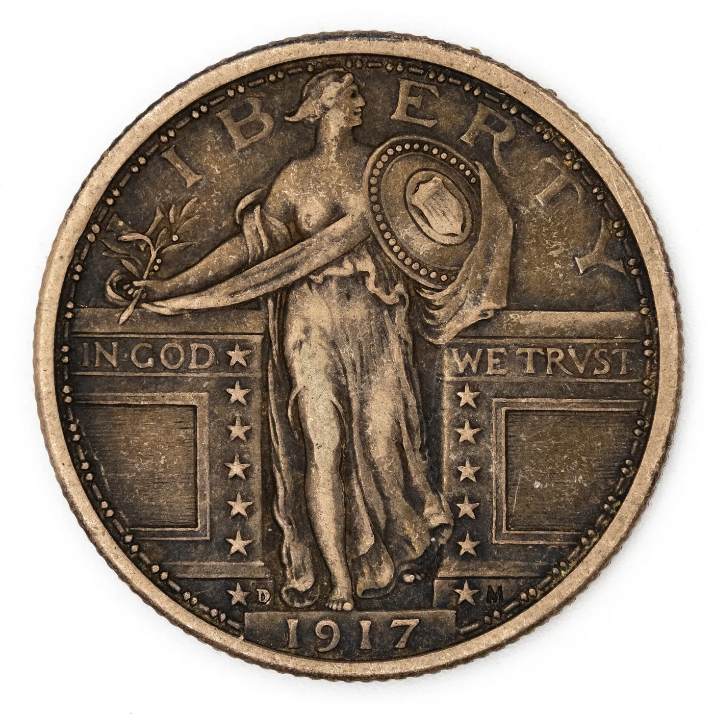 Obverse of a circulated and toned 1917-D Type 1 Standing Liberty quarter, with flattening on the head, the forward knee and the rim of the shield