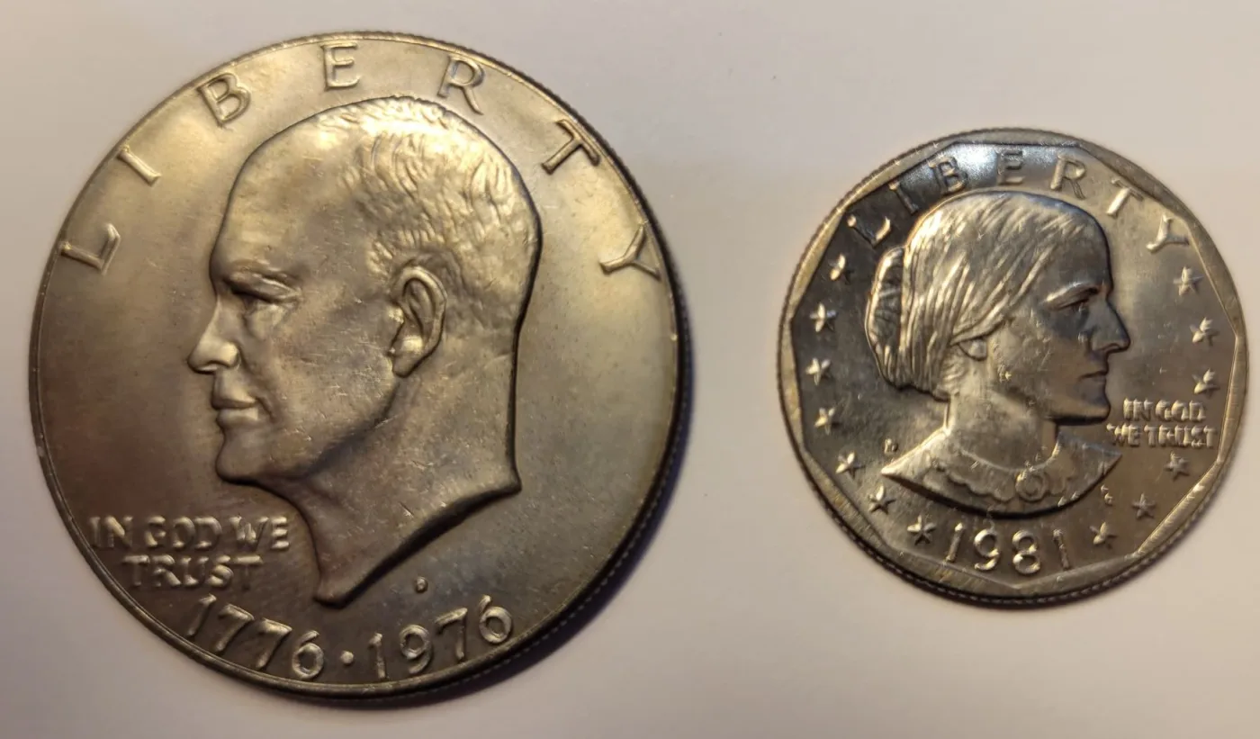 A Bicentennial Eisenhower dollar beside a 1981 Susan B. Anthony dollar, the Eisenhower substantially larger
