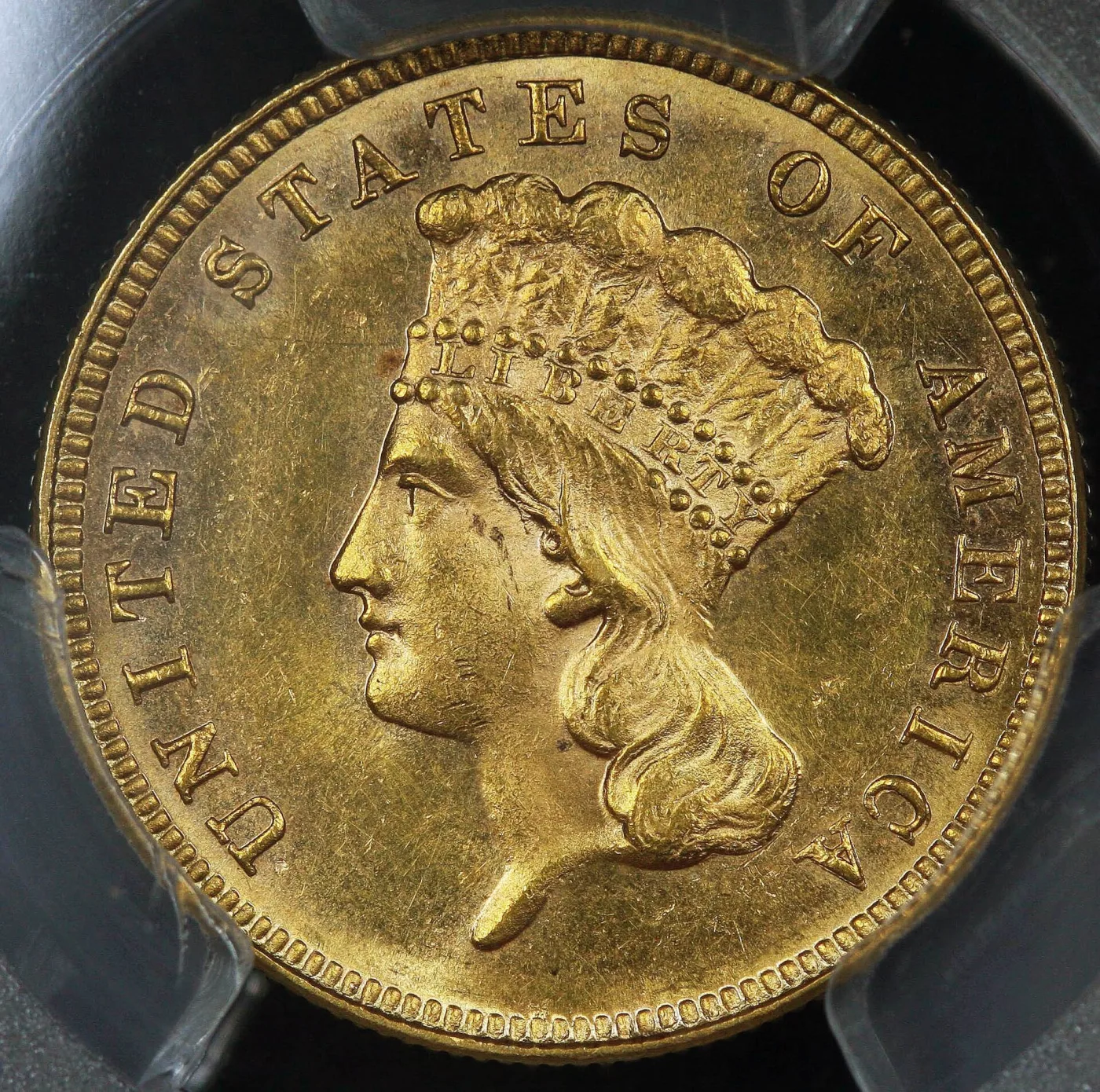 Indian Princess obverse of a Three Dollar Gold piece in a grading holder, headdress feathers, LIBERTY band and hair curls all fully struck