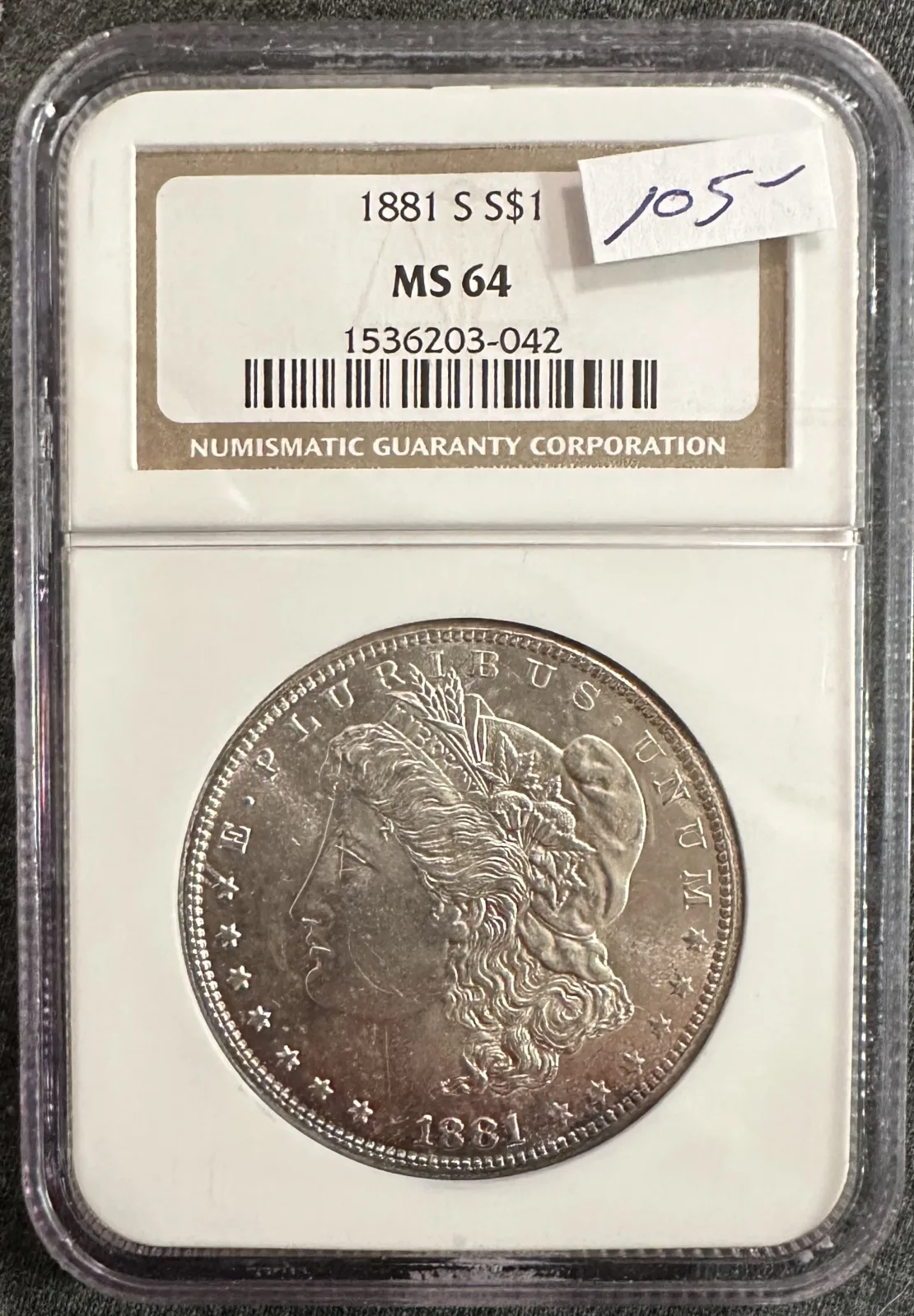 A Morgan silver dollar in a grading holder, the coin showing a coloured band around the rim, with the label above it