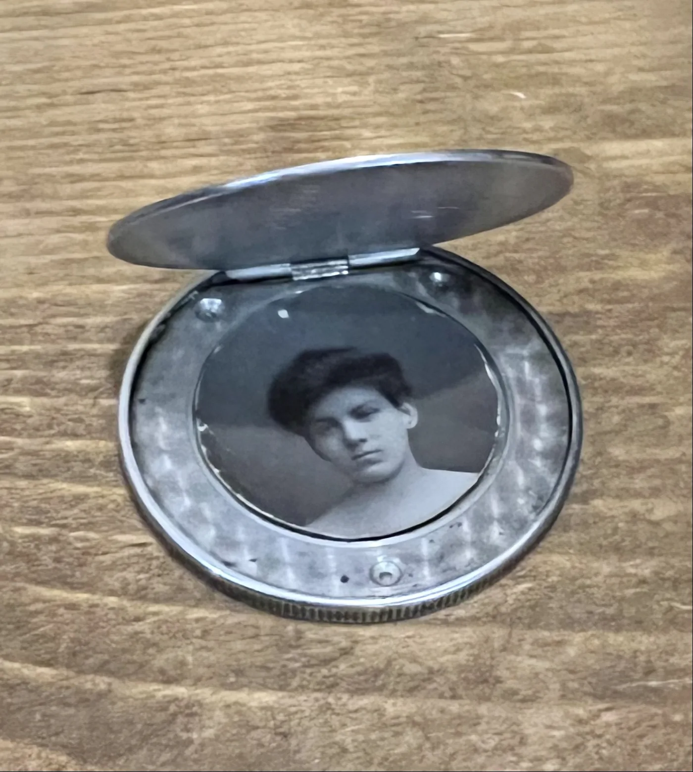 A Trade Dollar machined into a hinged locket, opened to show a hollow interior holding a small portrait photograph