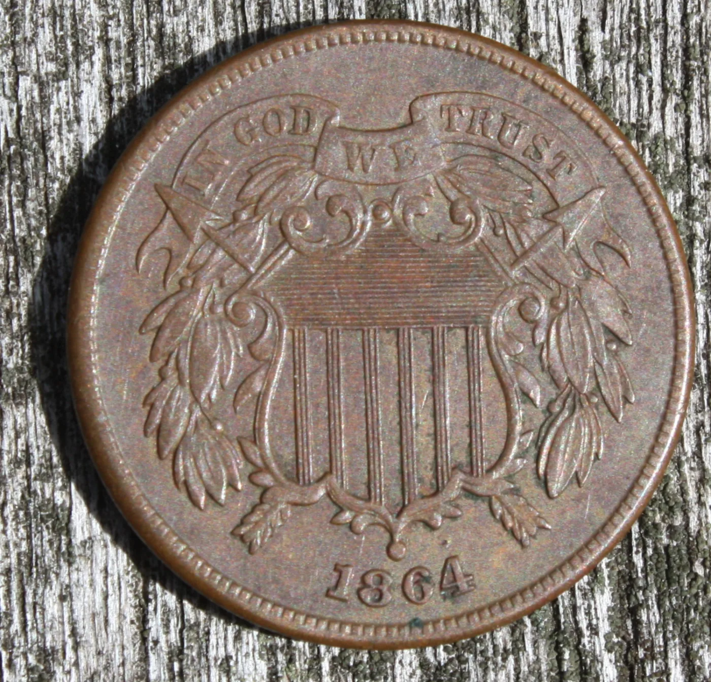Obverse of a circulated 1864 two cent piece with the four-digit date legible below the point of the shield