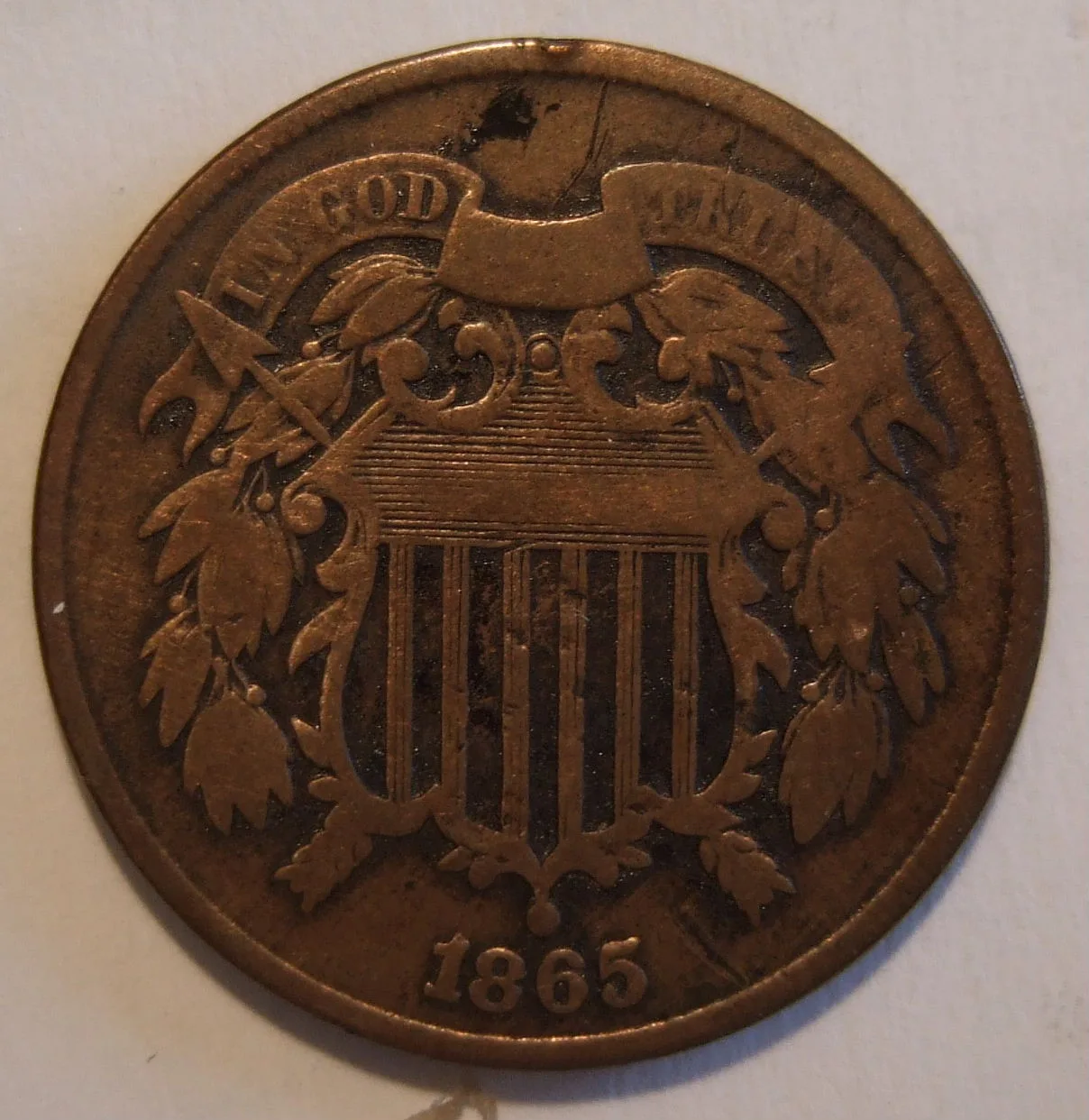 Obverse of a well-circulated 1865 two cent piece with the TRUST end of the motto banner worn nearly smooth
