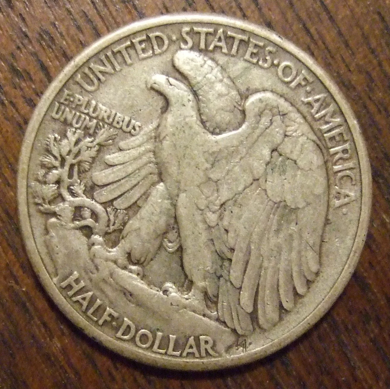 Reverse of a circulated 1941 Philadelphia Walking Liberty half dollar showing the eagle on a crag, the pine sapling, E PLURIBUS UNUM and no mint mark at the lower left