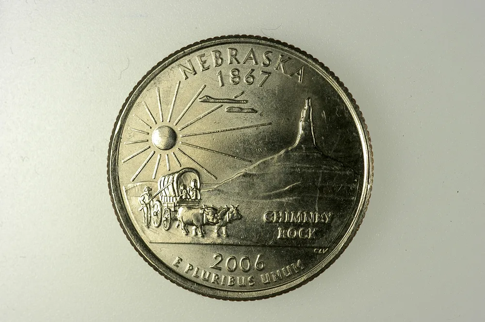 Reverse of a 2006 Nebraska state quarter showing a covered wagon drawn by oxen in front of Chimney Rock with a rayed sun above